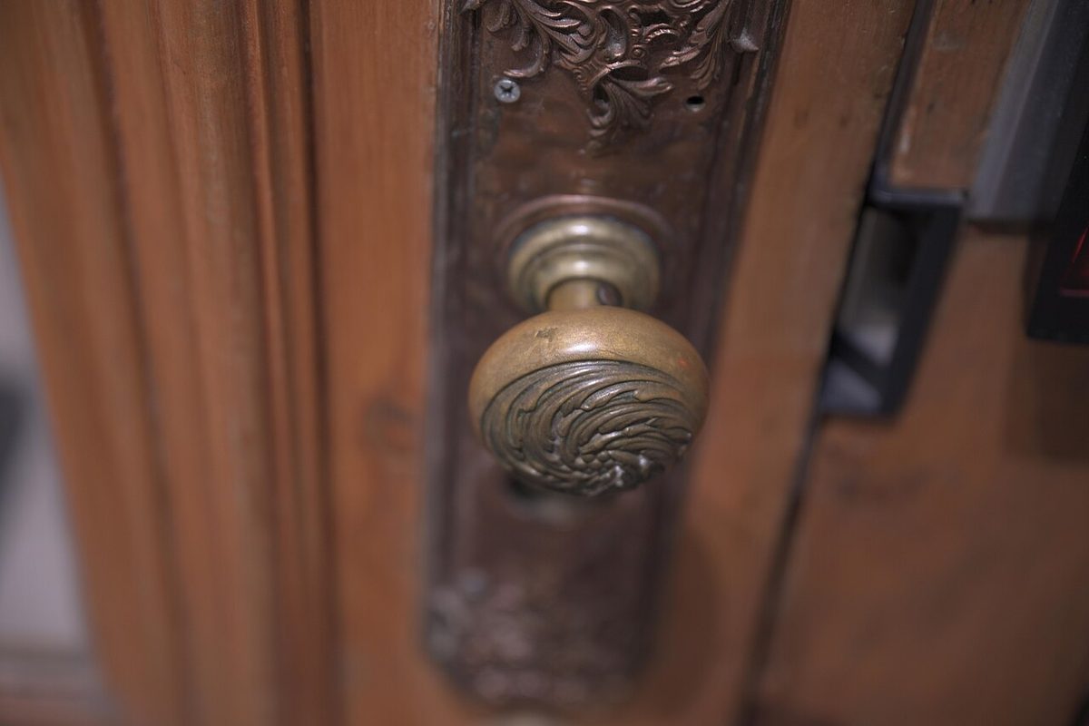 An old turned brass doorknob on a wooden door in Quebec City, the paint worn away around the grip. Not the one in the story.