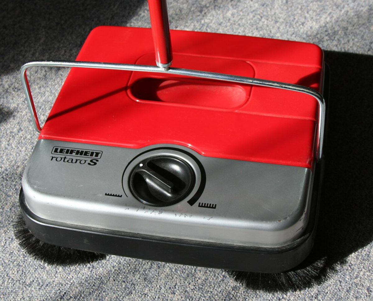 A Leifheit carpet sweeper, newer than the one in the story but built on the same idea: push it and the brushes turn.